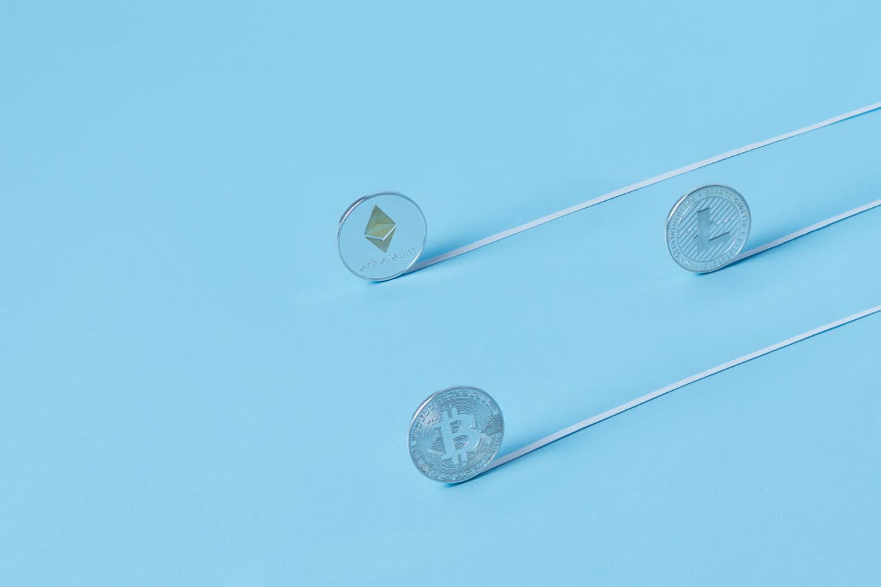 Minimalist image of Bitcoin, Ethereum, and Litecoin coins on a baby blue background.